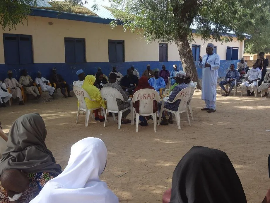 Kingsley Udo addressing a community gathering under trees in Bungudu, Zamfara State