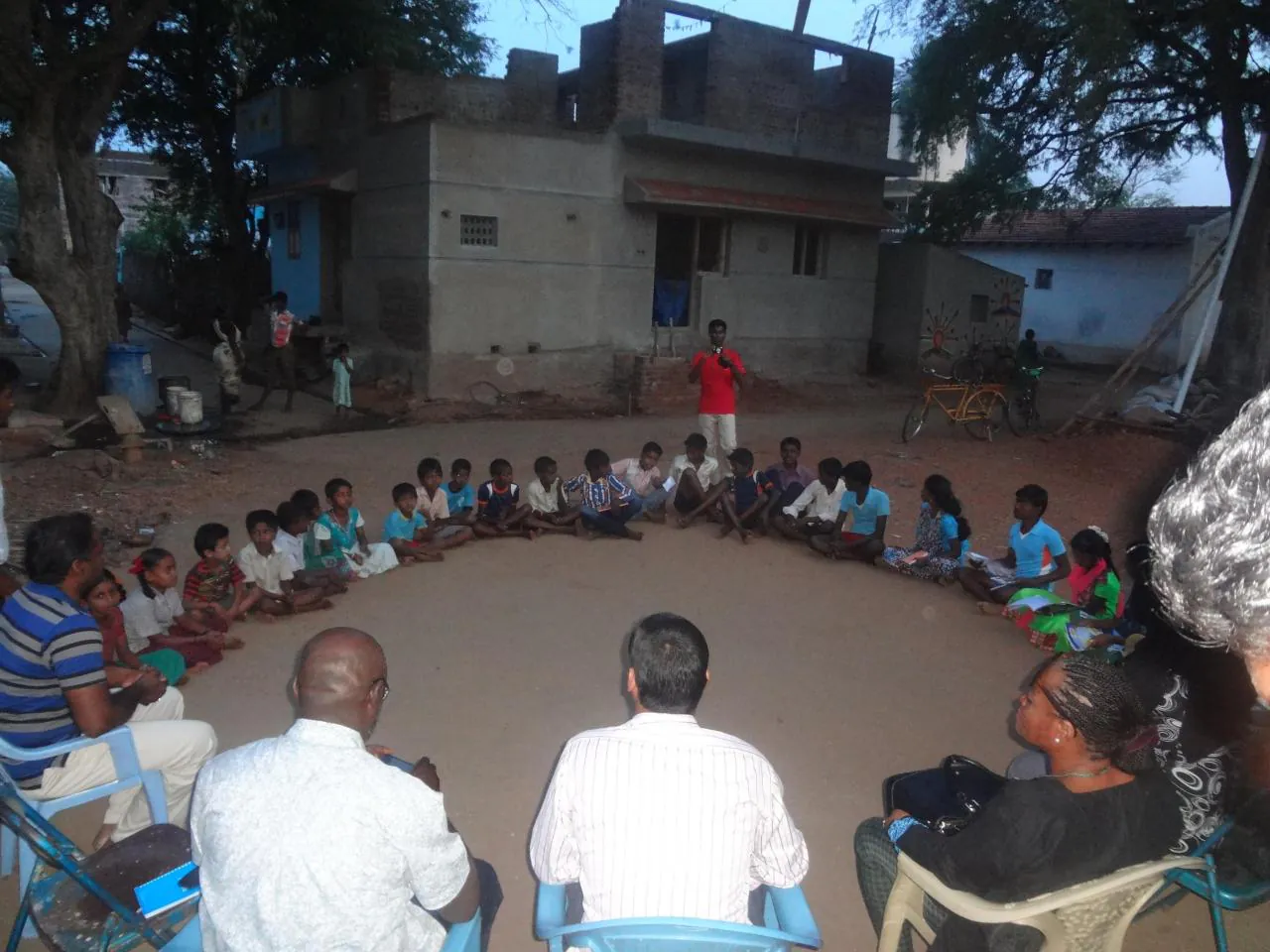 Children and facilitators seated in a circle in an inclusive neighbourhood space, India
