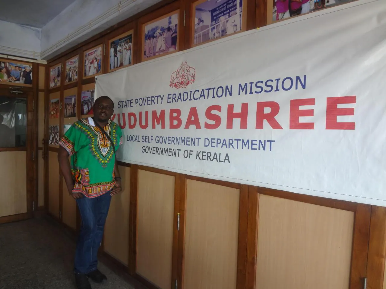 Kingsley Udo in front of a Kudumbashree banner, State Poverty Eradication Mission, Kerala