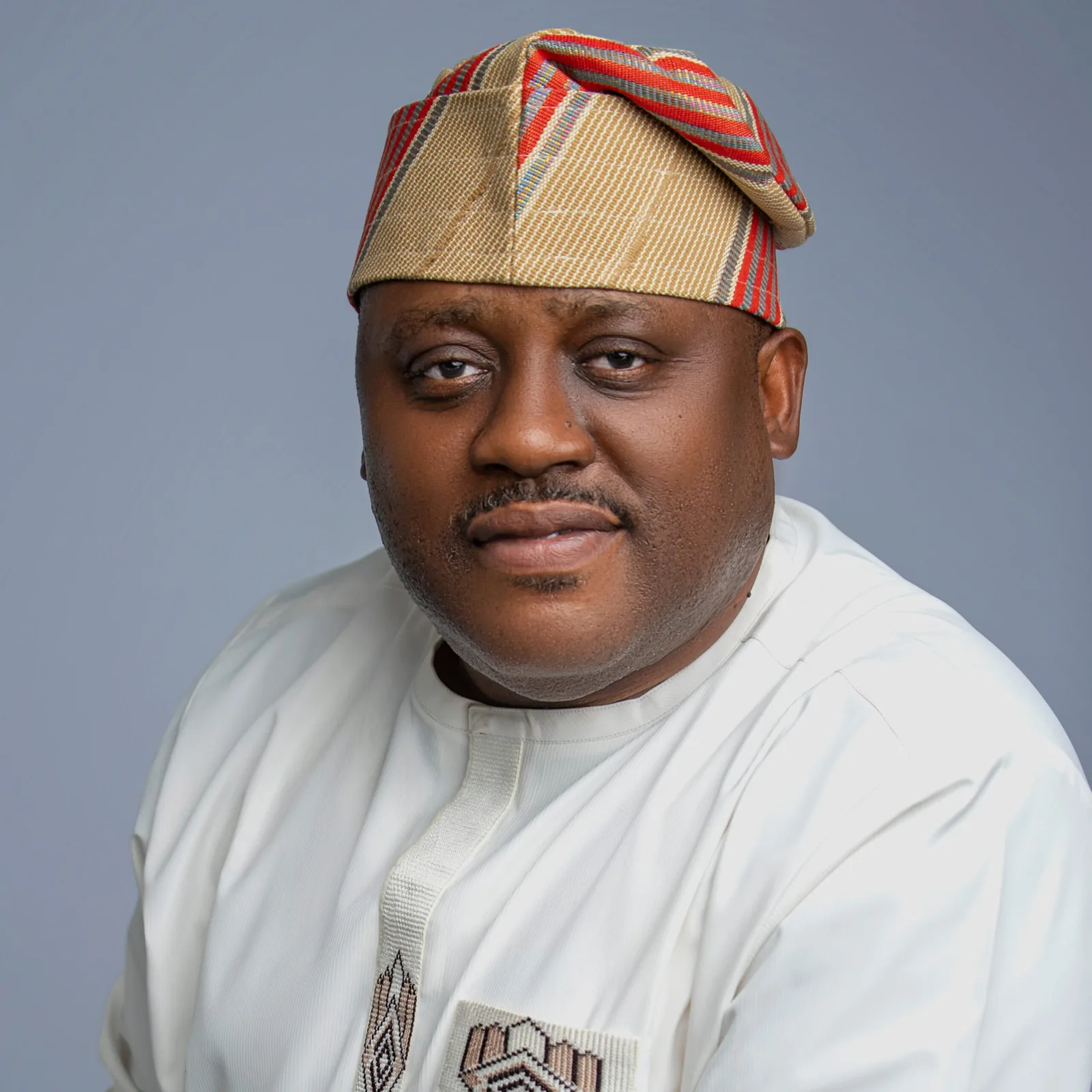 Dr Kingsley Udo in a white kaftan and gold and red aso-oke cap